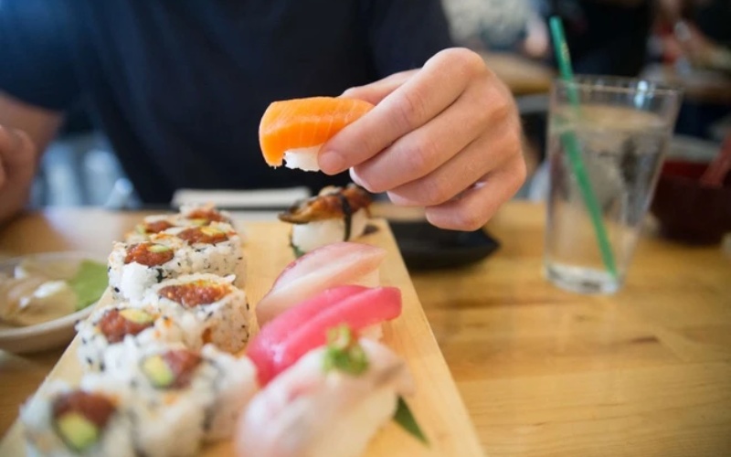 Hãy cầm miếng sushi bằng ngón cái và ngón giữa, ngón trỏ đặt lên phần thân